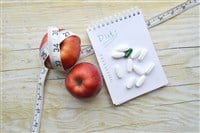 Two apples, measuring tape, pills and notebook - stock image