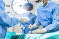 Surgeon and his assistant performing cosmetic surgery in hospital operating room. Surgeon in mask during medical procadure. Breast augmentation, enlargement, enhancement