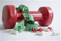 Dumbbells, measuring tape, weight loss pill capsules on a light background - stock image