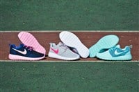 Three pairs of Nike Roshe Run sneakers, running shoes, trainers close up view, shot outdoors on sports field background. Sport and casual footwear concept. Krasnoyarsk, Russia - April 6, 2015