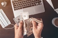 Businessman counting american dollar paper currency cash at office desk, top view of male hands with money