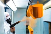 Powder coating of metal parts. A woman in a protective suit sprays powder paint from a gun on metal products - stock image