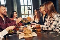 At daytime. Group of young friends sitting together in bar with beer.