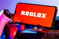 Kazan, Russia - August 25, 2021: Roblox is an online game platform and game creation system. A smartphone with the Roblox logo on the screen on the pile of the gamepads. - Stock Editorial Photography