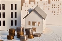 Houses models on white wooden table with coins, real estate concept - stock image