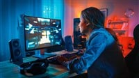 Gamer Girl Has a Tense Moment in Her First-Person Online Shooter Video Game on Her Computer. Room and PC have Colorful Neon Led Lights