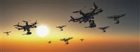 As the sun dips below the horizon, a squadron of drones takes to the sky, silhouetted against the fading light of dusk — Photo