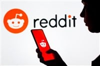 March 28, 2022, Brazil. In this photo illustration, a woman's silhouette holds a smartphone with the Reddit logo displayed on the screen and in the background