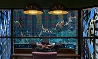 Photo of a businessman surrounded by stock market screens.