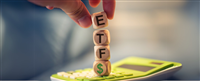 Close-up view of man forming acronym ETF with wooden cubes. A calculator in the composition. — Photo