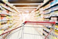 Empty shopping cart with abstract blur supermarket discount store aisle and product shelves interior defocused background - stock image