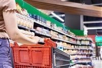 Shopping cart and woman at grocery store — Photo